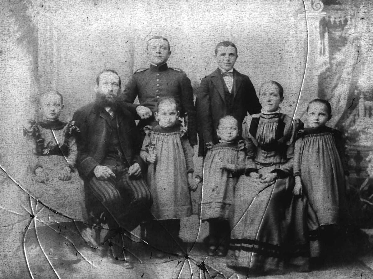 Original: Gruppenfoto einer Großfamilie mit acht Personen, Abzug mit Rissen und Flecken